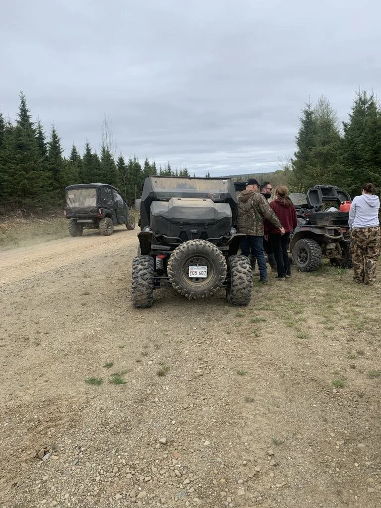 Side-by-sides and riders stopped on a gravel trail